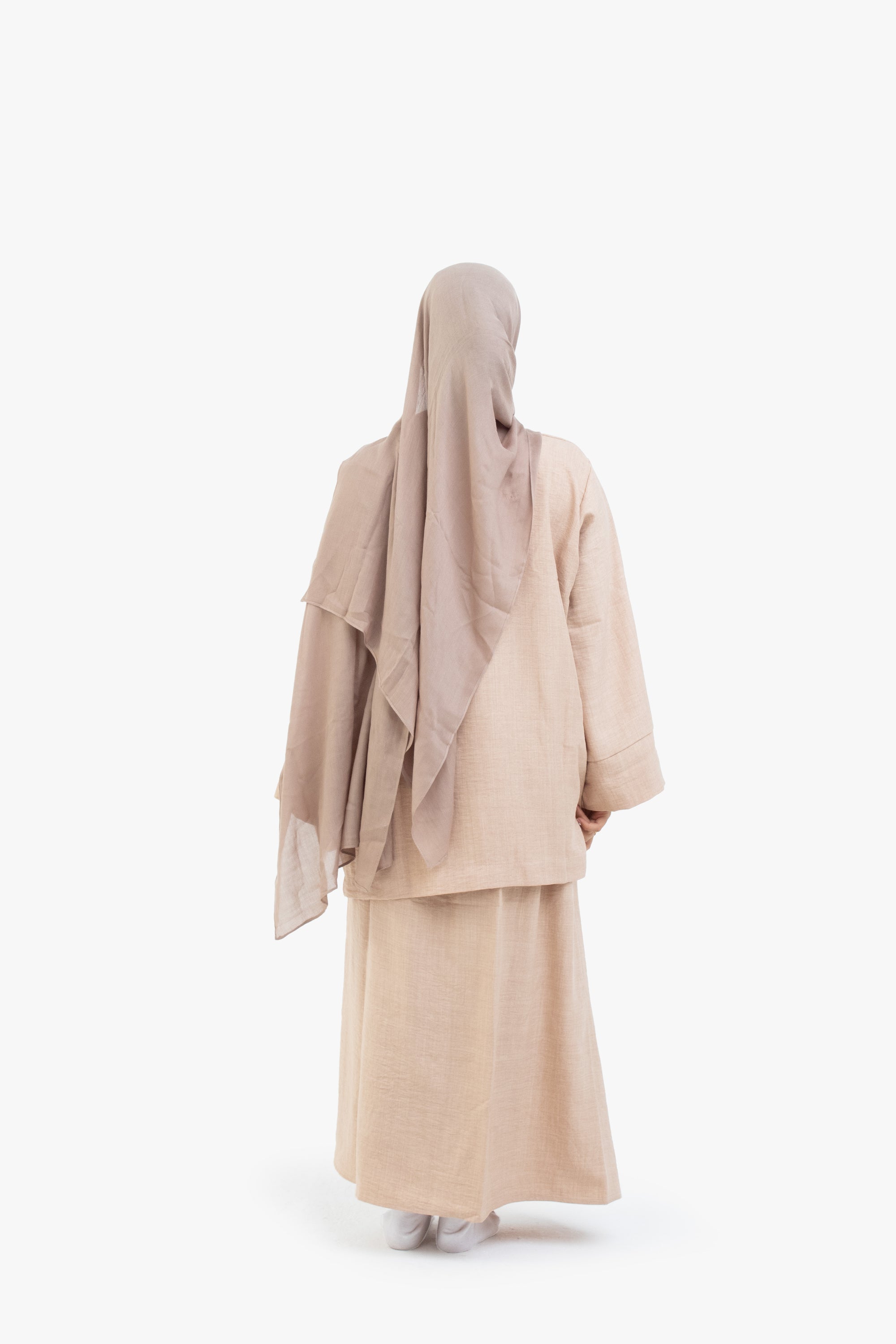 Person wearing a beige hijab and abaya on a white background