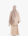 Person wearing a beige hijab and abaya on a white background